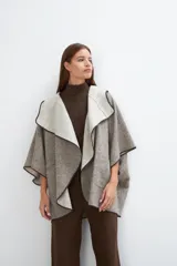 Ruana color crudo de lana fina sin teñir, con capucha, bolsillos y terminaciones envivadas. Tiene un broche para usar cerrada. Es una prenda oversize sin forro, cómoda, versátil y fácil de combinar.