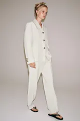 Pantalón ZARA Woman Collection de tiro medio y corte recto, confeccionado en hilatura con mezcla de lino en color blanco. Cuenta con cintura con trabillas, bolsillos laterales ocultos en costura, detalle de raya planchada y cierre frontal con cremallera, botón y ganchos metálicos.