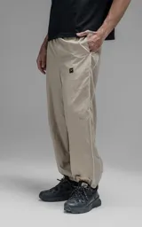 Pantalón deportivo de microfibra color beige, con corte regular y diseño de inspiración vintage. Presenta vivos laterales a contratono, cintura elástica y puños elásticos en los tobillos.