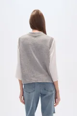 Chaleco de punto sin mangas en color beige con efecto confetti y diseño de jacquard frontal en color negro con motivos de herradura, luna y pájaro. Cuenta con cuello redondo y acabados acanalados.