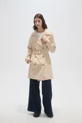 Trinchera de corte clásico, color negro, con cierre frontal de doble botonadura, solapas amplias y cinturón ajustable con hebilla en la cintura.