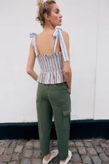Pantalón cargo de tiro medio con pinzas delanteras, bolsillos laterales de plastrón y cierre frontal con cremallera y botón. Presenta una pernera holgada que se estrecha ligeramente hacia el bajo.