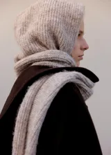 Bufanda de punto grueso en color beige melange, con diseño envolvente que incluye una capucha integrada.