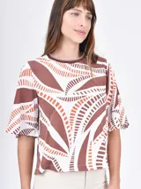 Blusa de mangas cortas con volados, color beige con estampado de líneas onduladas blancas.