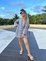 Vestido corto dorado con textura brillante, corte holgado, mangas largas con volados y cuello redondo.