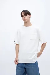 Remera color crudo de algodón con calce oversize, manga corta, cuello redondo y estampa en la espalda con texto en color negro.