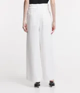 Pantalón de corte amplio tipo pantalona, confeccionado en tejido plano de poliéster. Presenta cintura alta con cinturón elástico integrado que incluye hebilla metálica, pliegues frontales y bolsillos laterales.