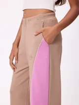 Babucha de corte holgado en color beige con paneles laterales en color fucsia y vivos blancos. Presenta cintura elástica y logo bordado en la parte superior.