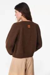 Cardigan de lana merino color crudo, de tejido de punto, manga larga y cierre frontal con botones.