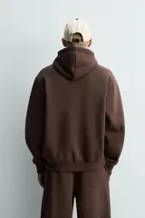 Sudadera con capucha de corte relajado, confeccionada en tejido de algodón con interior perchado. Presenta mangas largas, bolsillo frontal tipo canguro y terminaciones en rib.