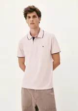 Chomba de piqué color rosado con cuello y puños en contraste color azul marino. Presenta cierre frontal con botones y un pequeño bordado en el pecho.