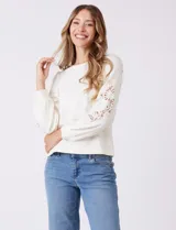 Buzo blanco de modal, corte clásico, con mangas largas abullonadas y apliques de crochet floral en los hombros y parte superior de las mangas.