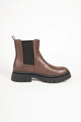 Botas Chelsea de símil cuero marrón, con punta redonda, paneles elásticos negros en los laterales, presilla trasera y suela de plataforma dentada.