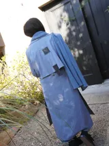 Impermeable largo color celeste con detalles en tweed en puños y solapa, con cinturón y corte clásico.