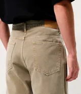 Pantalón recto de sarga color beige, con cierre frontal de botón y cremallera, y bolsillos funcionales.