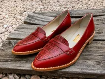 Mocasines de cuero color rojo con diseño de textura combinada, presentando una puntera con efecto reptil y cuerpo liso. Poseen costuras a la vista, vira de suela natural cosida y taco bajo foliado.