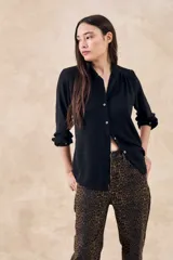Blusa negra con cuello mao, calce al cuerpo y mangas 3/4 con puños abotonados. Cierre frontal con botones.