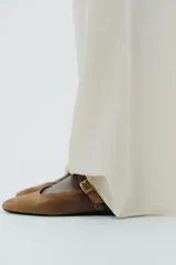 Zapato plano tipo bailarina en serraje color marrón. Tiene escote redondo y cierre mediante hebilla en el empeine.