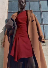 Vestido corto de color rojo con diseño asimétrico, cuello escotado y drapeado en la cintura. Confeccionado en tejido fluido con textura y cierre de cremallera lateral.