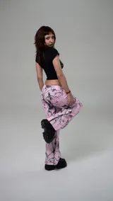 Pantalon de corte recto y tiro alto con estampado de camuflaje en tonos rosados y negros, con detalles gráficos de corazones y estrellas.