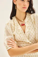 Camisa corta tipo crop top de viscosa con destellos de lurex dorado. Presenta escote en V cruzado con volados, mangas al codo con frunces en los hombros y puños elastizados.