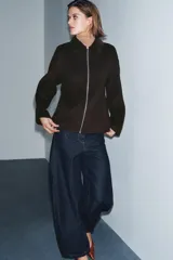 Chaqueta de corte recto confeccionada en hilatura con lana, en color marrón oscuro. Presenta cuello clásico en tejido efecto piel de ante, cierre frontal con cremallera metálica y manga larga.