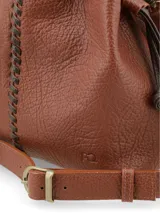 Cartera tipo bandolera de cuero graneado color marrón, formato saco con cierre de tientos ajustables y costura central decorativa a contratono. Cuenta con correa regulable.