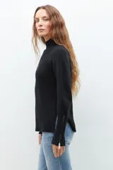 Polera de punto color ladrillo, de cuello alto y mangas largas con cierre en los puños.