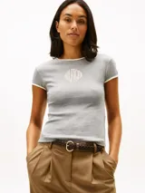 Remera de corte slim gris con ribetes blancos en cuello y mangas, de manga corta y cuello redondo. Presenta un bordado frontal con el texto "Hilfiger".