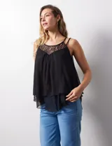Blusa negra de gasa con breteles finos trenzados, escote redondo y capas superpuestas de encaje y gasa en el frente.