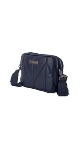 Bandolera de diseño acolchado con costuras geométricas, color verde oliva. Cuenta con doble compartimento con cierre metálico, placa metálica con logo en el frente y correa de cinta ajustable y extraíble.