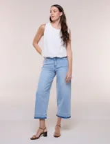 Jean cropped de denim celeste, con tiro alto, pernera ancha y recta, y diseño de cinco bolsillos. Presenta un dobladillo bicolor con flecos en tono más oscuro.