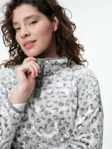 Buzo de dormir de tela fleece con estampado animal print en tonos grises y blancos. Presenta cuello alto con cierre de botones a presión y mangas largas.