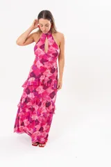 Vestido largo fucsia con estampado abstracto, cuello halter con abertura en forma de lágrima y volados en la falda.