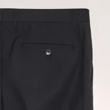 Pantalón de vestir de corte slim, color negro, con cierre de botón y cremallera, bolsillos laterales y trabillas para cinturón.