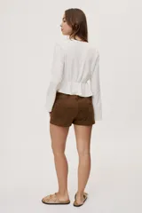 Short de tiro bajo con textura efecto gamuza color beige, bolsillos delanteros y detalle de cordones entrecruzados en la parte frontal.