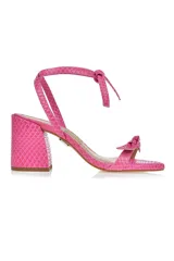 Sandalia de tacón color rosa con estampado de piel de serpiente, tira delantera con nudo y tira para atar al tobillo.