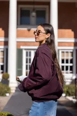 Campera bomber oversize color borgoña de nylon con cierre frontal, bolsillos laterales con cierre, puños y cuello tejidos al tono.