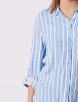 Camisa celeste con rayas verticales blancas, de corte recto y manga 3/4 regulable con presilla y botón.