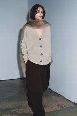 Chaqueta de punto color beige, confeccionada en 100% lana, con escote en pico, manga larga y cierre frontal con botones.