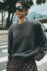 Sweater de punto color verde oscuro, con cuello redondo, manga larga y hombreras marcadas.