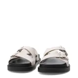 Sandalias Miss Carol modelo Brix, color marfil, con dos tiras cruzadas ajustables mediante hebillas metálicas plateadas y suela plana de goma negra.