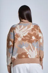 Sweater de punto color marrón con cuello alto y estampado botánico en tonos beige y gris.