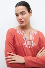 Remera blanca de manga larga con bordado floral azul en el escote.