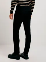 Pantalón de jean corte skinny, color azul medio, con diseño de cinco bolsillos y cierre frontal con botón y cremallera.