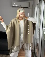 Poncho de tejido suave color blanco, con diseño abierto y flecos en el ruedo inferior.