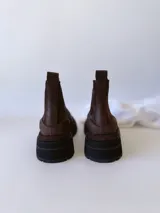 Bota Chelsea de cuero color marrón chocolate con elástico lateral negro y suela track color negro.