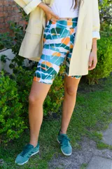 Calza corta de lycra con estampado abstracto en tonos verde, naranja, celeste y blanco.