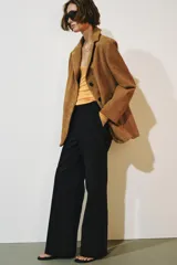 Pantalón de tiro medio color negro con trabillas en la cintura, bolsillos laterales ocultos y pierna recta. Cierre frontal con cremallera, botón y ganchos metálicos.