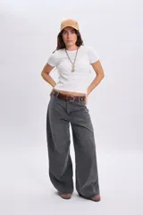 Pantalón jean ancho color gris claro, de corte holgado y tiro medio con estampa circular en el bolsillo trasero.